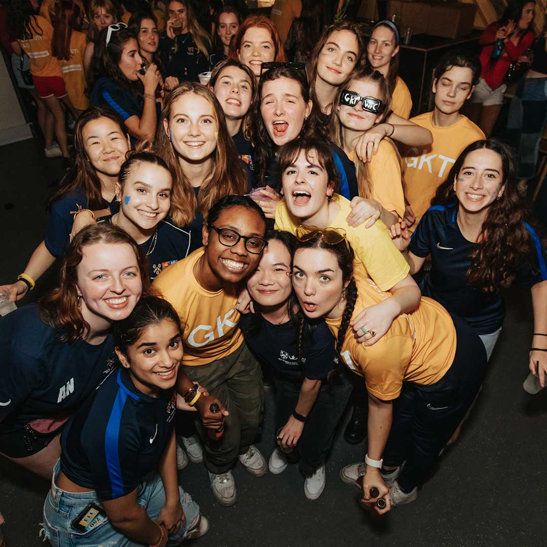 A group of students all laughing and pulling faces at the camera on a sports night out