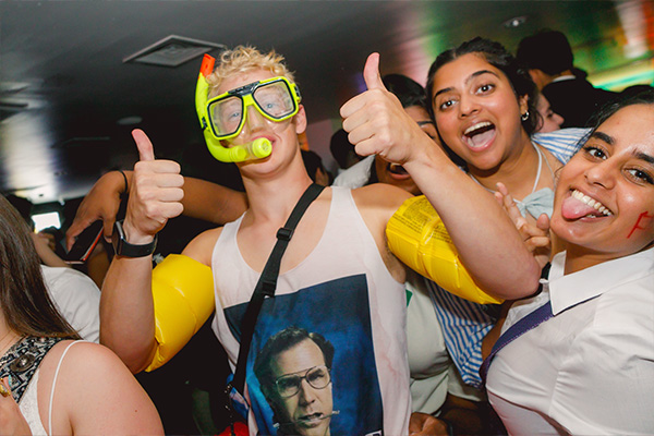 A student at a themed club night wearing a green snorkle mask